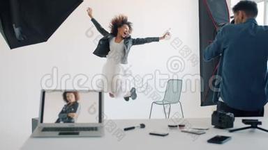 快乐的年轻女子跳着跳着，在摄影棚和摄影师一起玩摆拍
